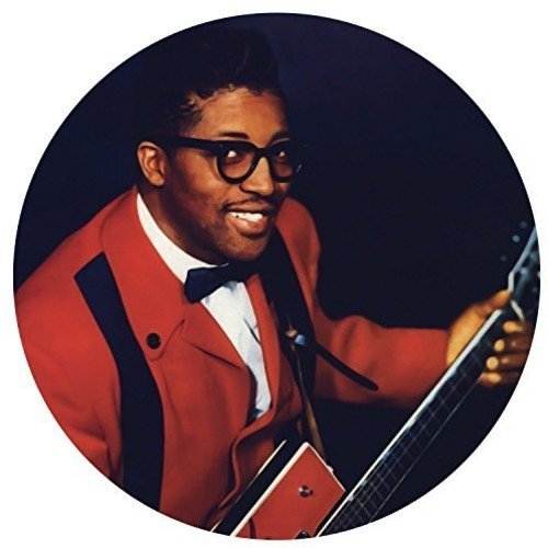"Bo Diddley in a red suit holding a guitar, circular image on a white background."