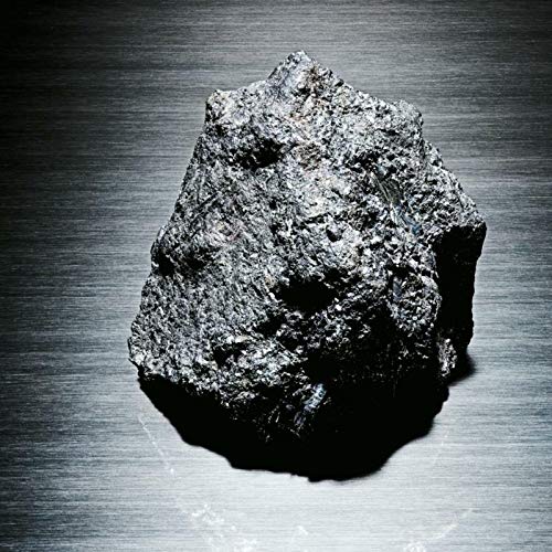 A dark, rough rock or stone is centered on a brushed metal surface.