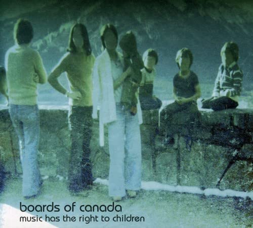 A grainy, blue-tinted vintage photo shows several people standing and sitting outdoors.