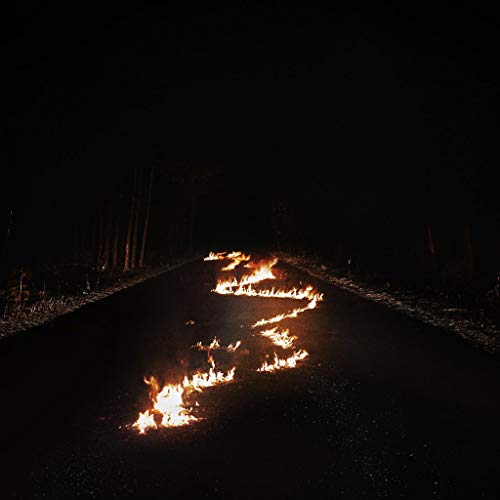 Flames forming a winding line on a dark asphalt road at night.