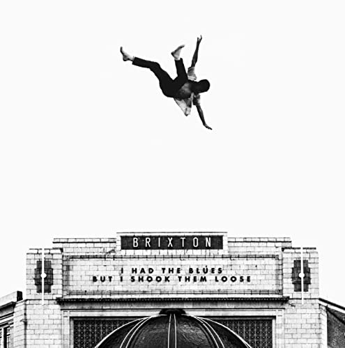 Black and white image of a person mid-air above a building.