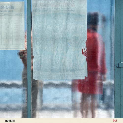 Vinyl record cover with blurred figure seen through textured glass.