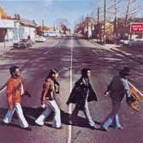 Album cover: four figures walking down a sunlit street.
