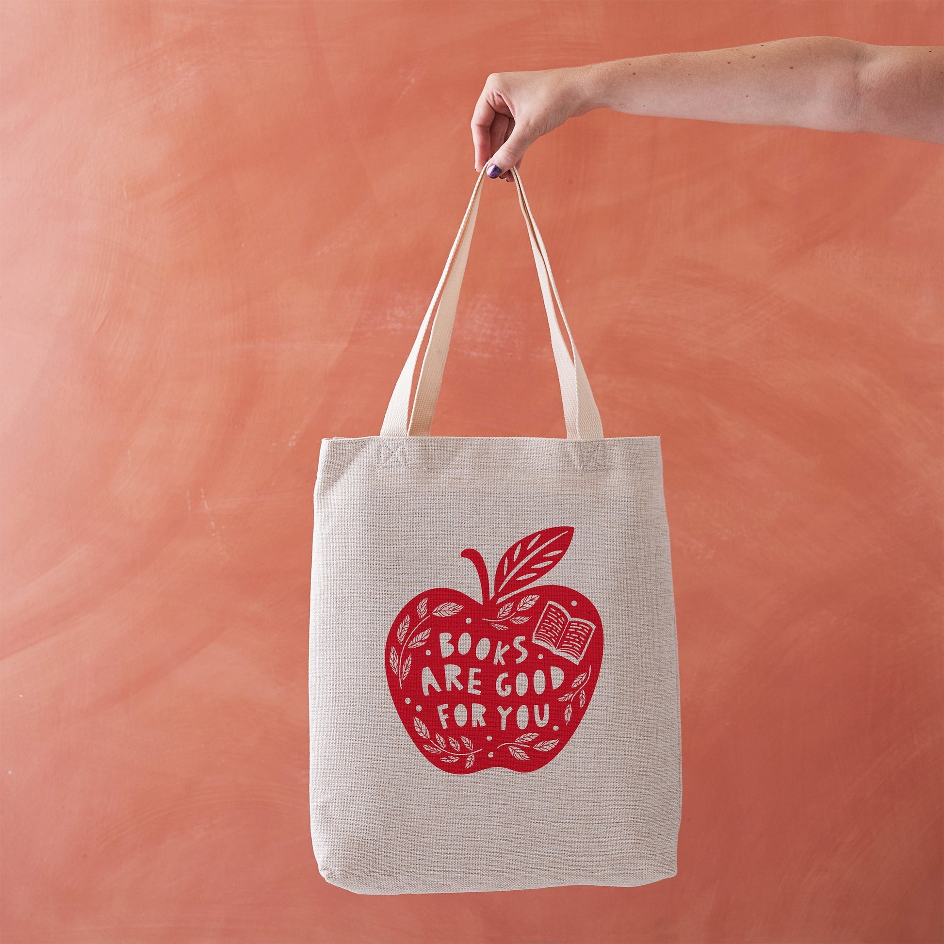 Canvas tote bag with a red apple and text reading "Books are good for you".