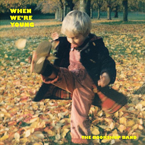 A child kicks through autumn leaves in a park, with album title and band name.