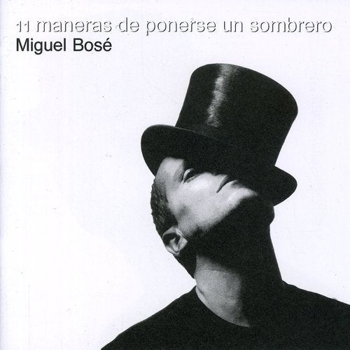 Black and white portrait of Miguel Bosé wearing a top hat, looking up.