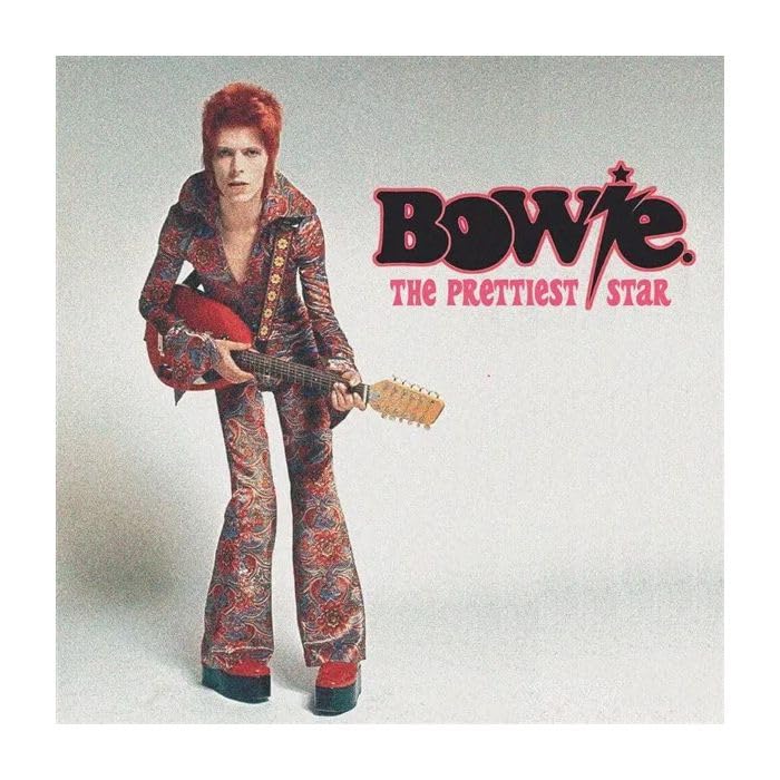 David Bowie in patterned suit holding a red electric guitar.