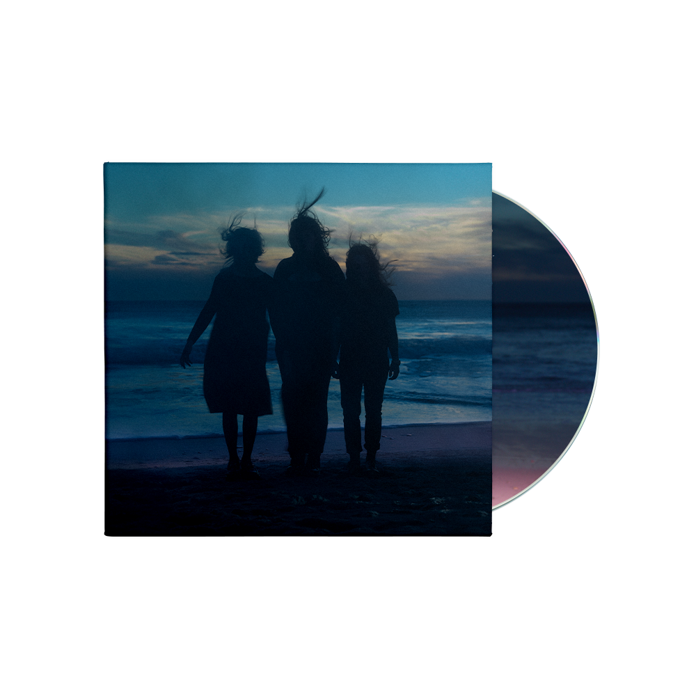 Silhouettes of three people standing on a beach at dusk on a CD cover.