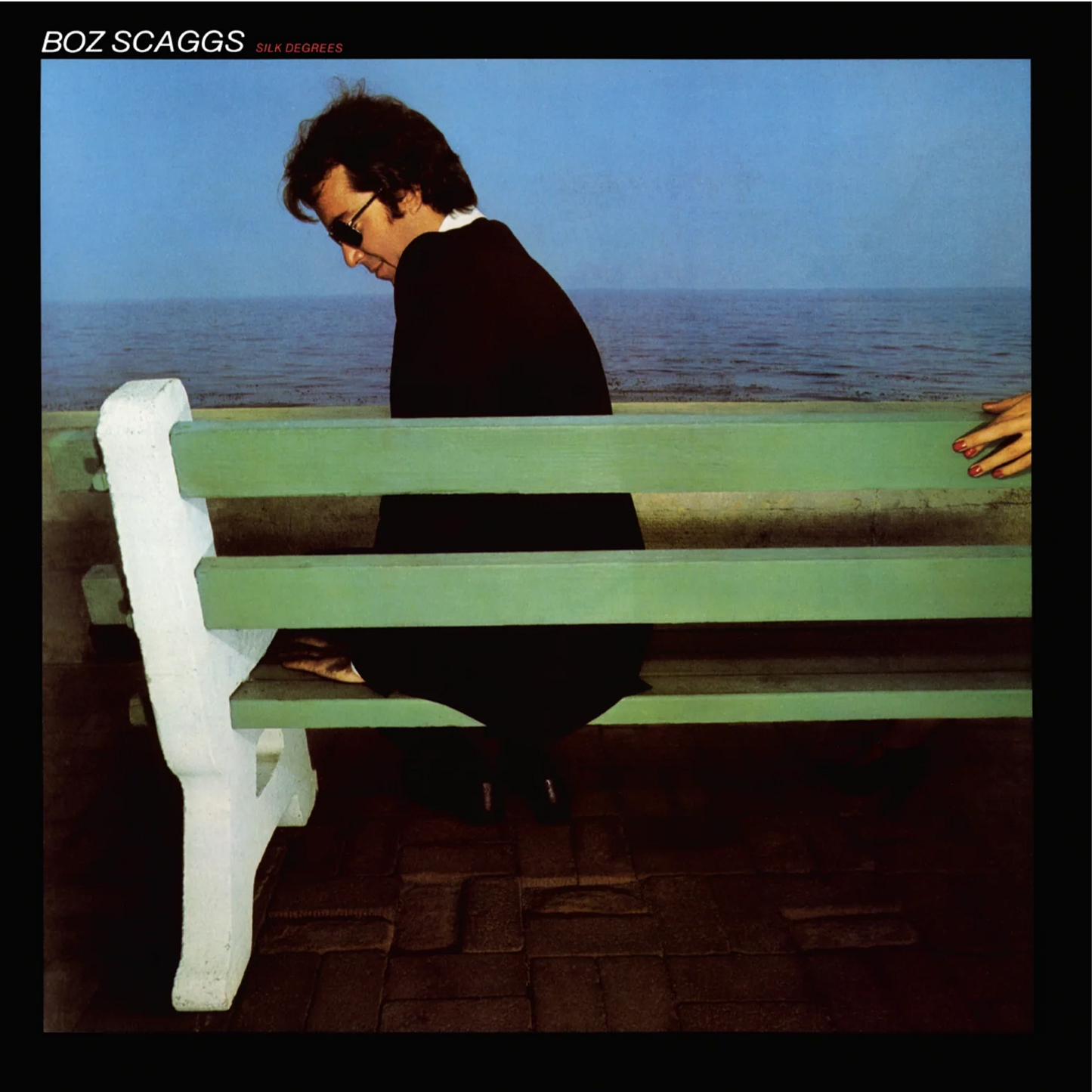Boz Scaggs sitting on a green bench overlooking the ocean on a vinyl cover.
