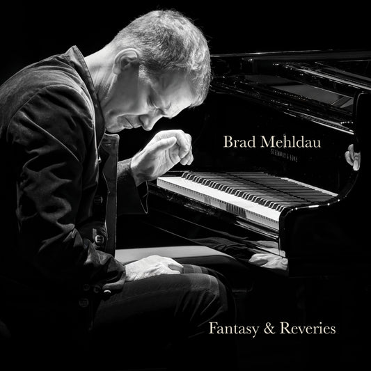 Black and white photo of Brad Mehldau playing a grand piano.