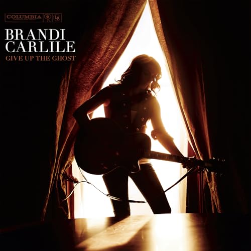 Brandi Carlile with guitar silhouetted in a bright window opening.
