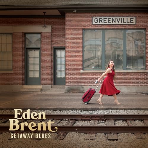 CD cover: woman with suitcase walks by a brick train station.