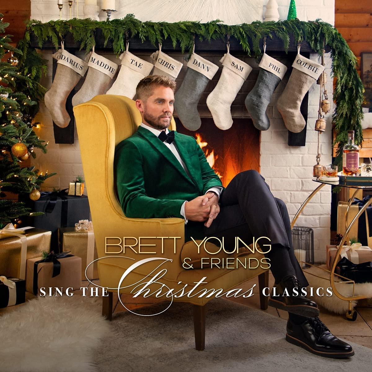 Brett Young in green velvet suit, seated by a decorated fireplace.