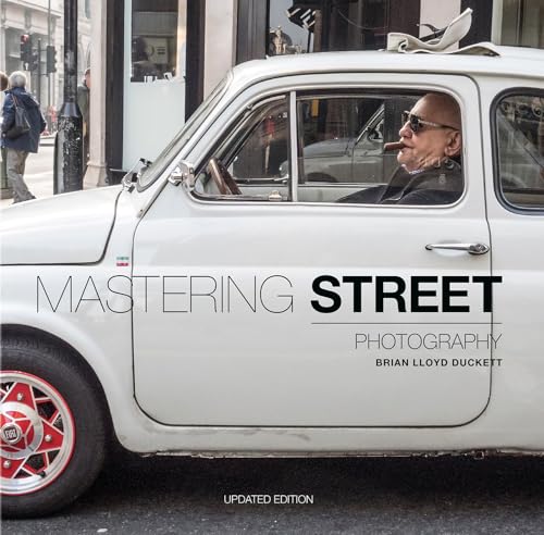 A man with sunglasses and a cigar sits inside a white vintage Fiat car.