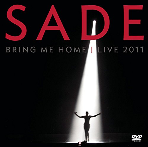 Sade stands in a bright spotlight on a dark stage on this DVD cover.