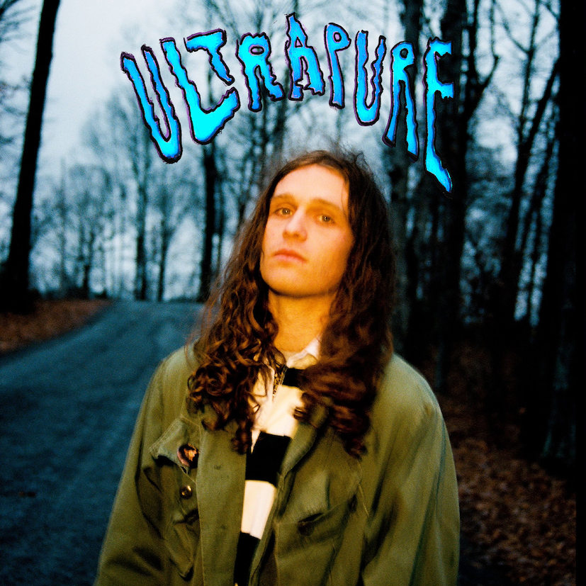 "Album cover featuring a man with long hair standing on a forest road."