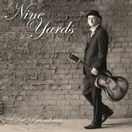 CD cover: man in suit with guitar against brick wall.