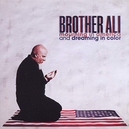Brother Ali kneeling in prayer on an American flag against a textured white background.