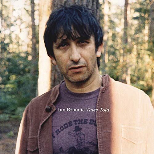 Album cover featuring a man in a forest, wearing a brown jacket over a graphic t-shirt.
