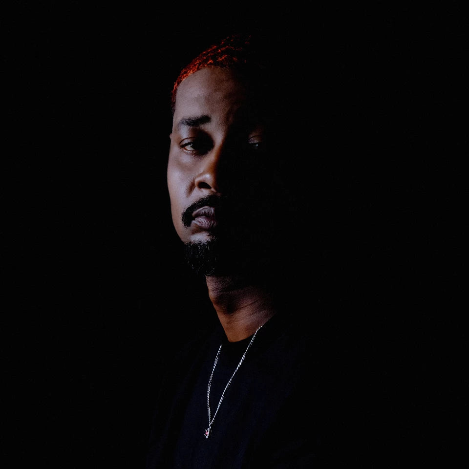 Danny Brown portrait, facing slightly right, with dark background.