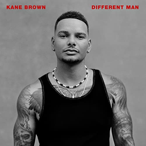 Black and white portrait of Kane Brown with tattoos and necklaces.