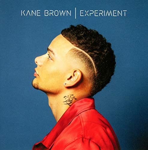 Profile view of Kane Brown wearing a red shirt against a blue background.