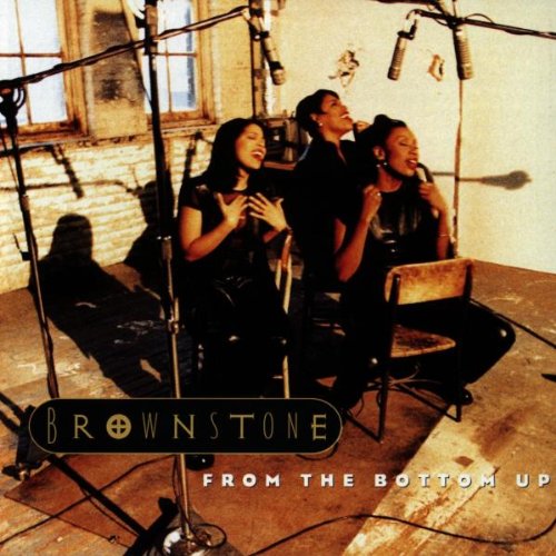 Three women in black singing into microphones in a rustic studio setting.
