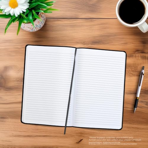 Open black journal with lined pages, a pen, coffee, and a daisy.