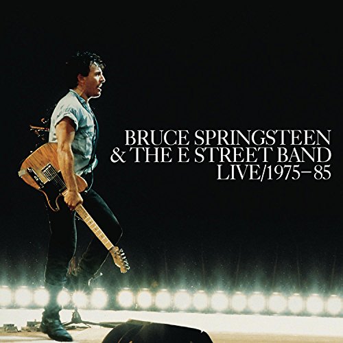 Bruce Springsteen performing on stage with a guitar against a dark background.