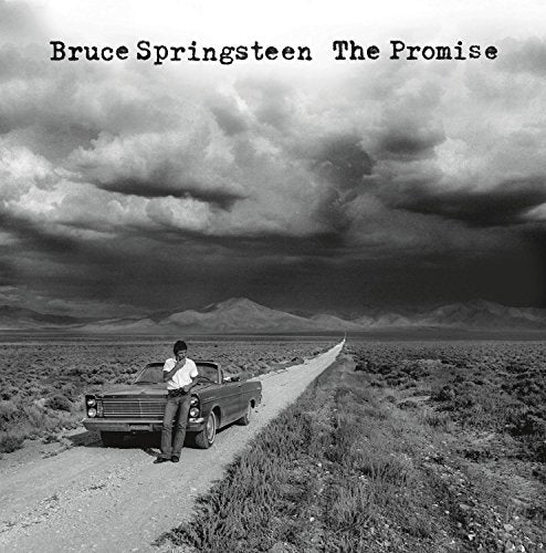 Black and white album cover: man and car on a desert road.