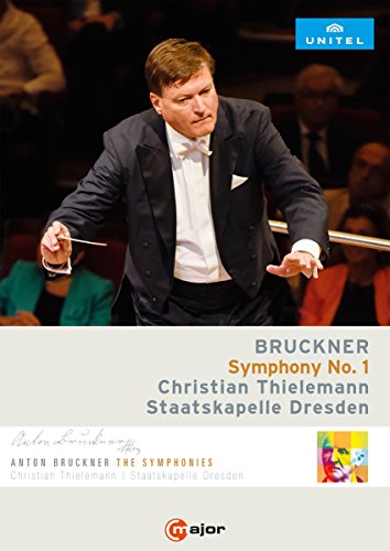 Conductor Christian Thielemann in a tuxedo, holding a baton, with audience in the background.