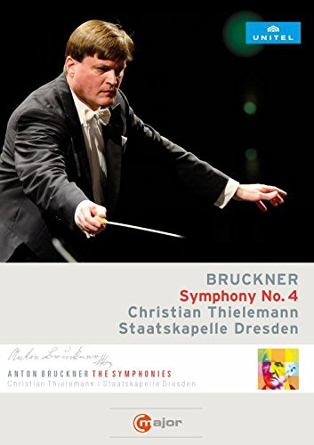 Conductor Christian Thielemann in a black suit, holding a baton, against a black background.