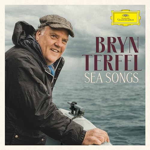 Bryn Terfel wearing a flat cap on a boat with the sea in background.
