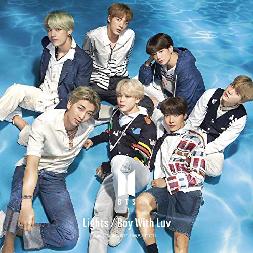"Seven young men sitting in a blue pool, wearing casual clothing."