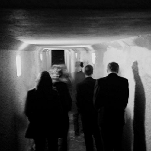 Black and white vinyl record sleeve with people walking down a dimly lit corridor.