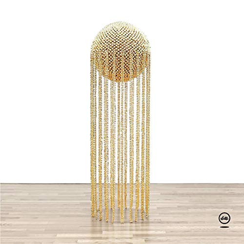 A gold, beaded, jellyfish-shaped decoration stands on a light wooden floor against a white wall.
