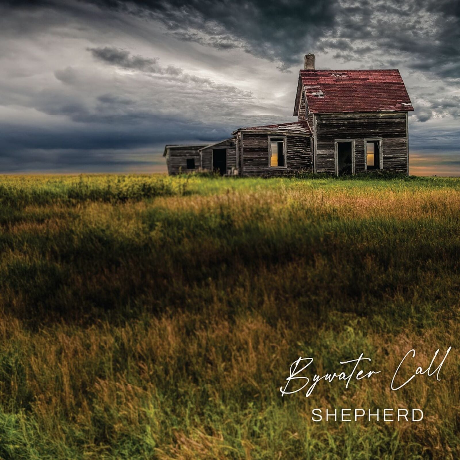 Dilapidated wooden house in a grassy field under a stormy sky.