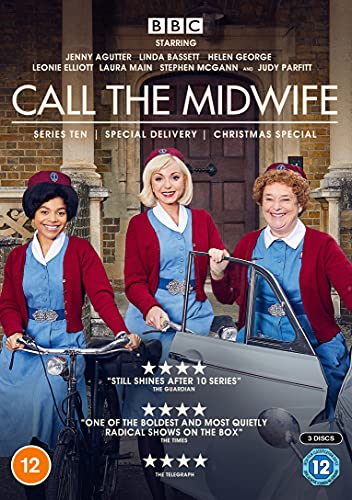 Three midwives in blue uniforms and red cardigans stand outside a brick building.
