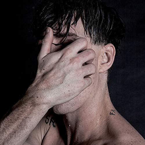 Close-up of a man with wet hair covering his face with his hand.