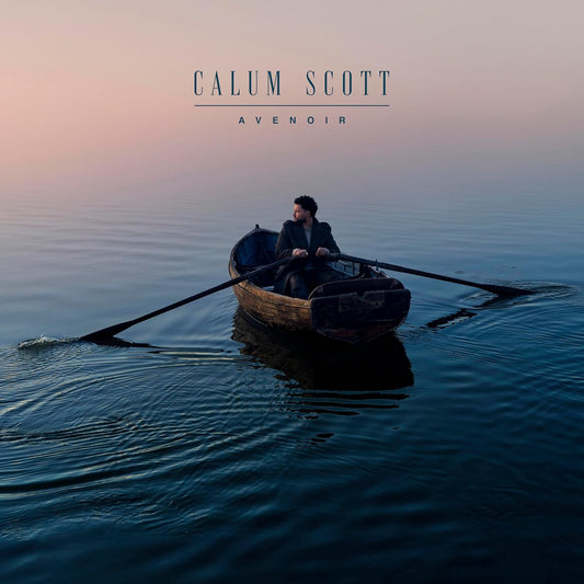 Calum Scott rowing a small boat on calm water at sunrise under a hazy sky.