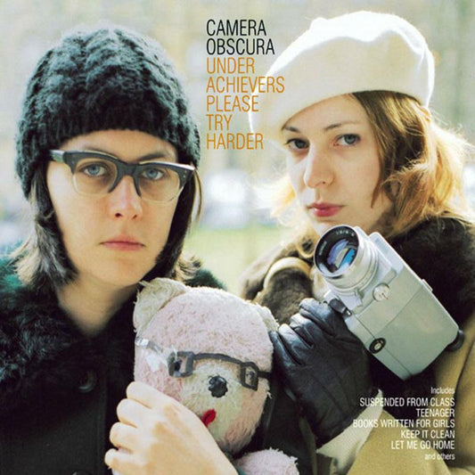Two women, one with a beanie and one with a beret, holding a camera.