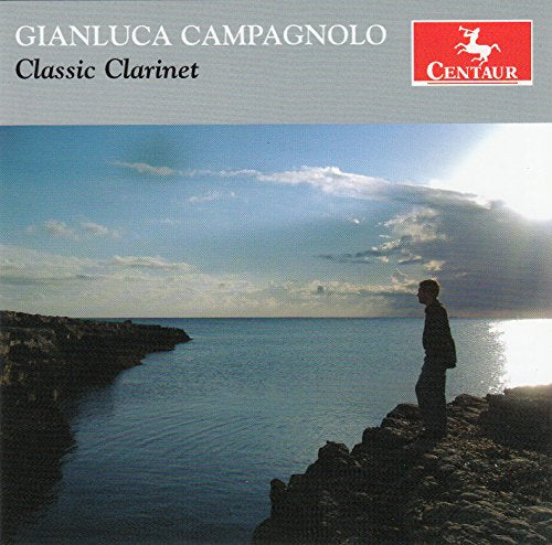 A CD cover with a man standing on a rocky shore, overlooking water.