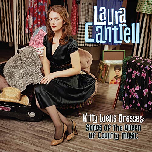 Woman in black dress sits amidst dresses, suitcase, and hat on album cover.