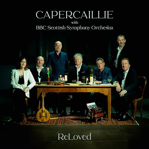 Capercaillie band members seated around a table with instruments and wine.