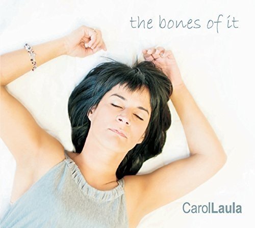 Carol Laula with eyes closed, arms raised above her head on a white background.