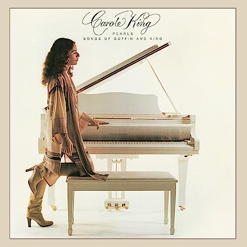 Carole King sits at a white piano, profile view, album cover.
