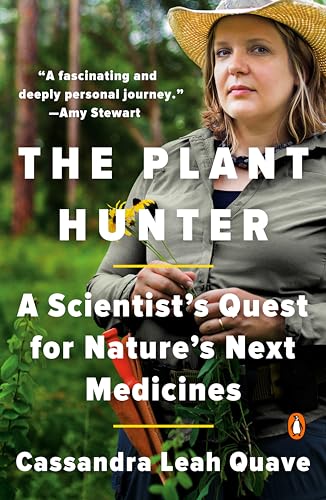 A woman wearing a sun hat and field gear holds plants in a forest.