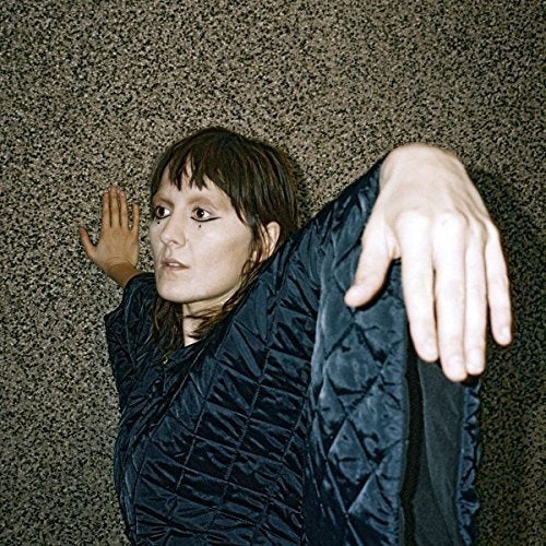 Cate Le Bon album cover: woman in dark jacket against textured wall.