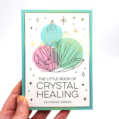 A hand holds a book titled The Little Book of Crystal Healing with crystal illustrations.