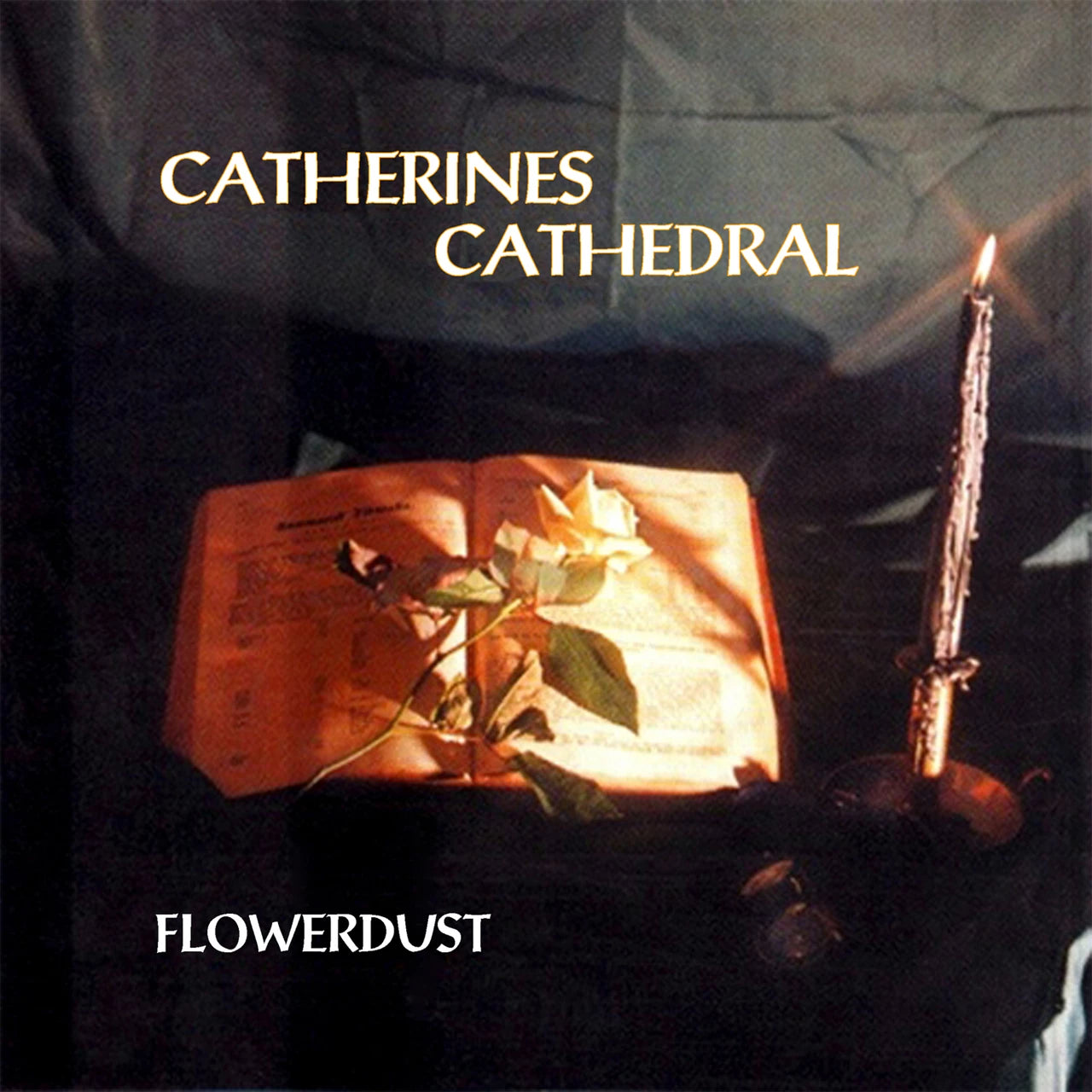 Dark album cover with open book, flower, and burning candle.